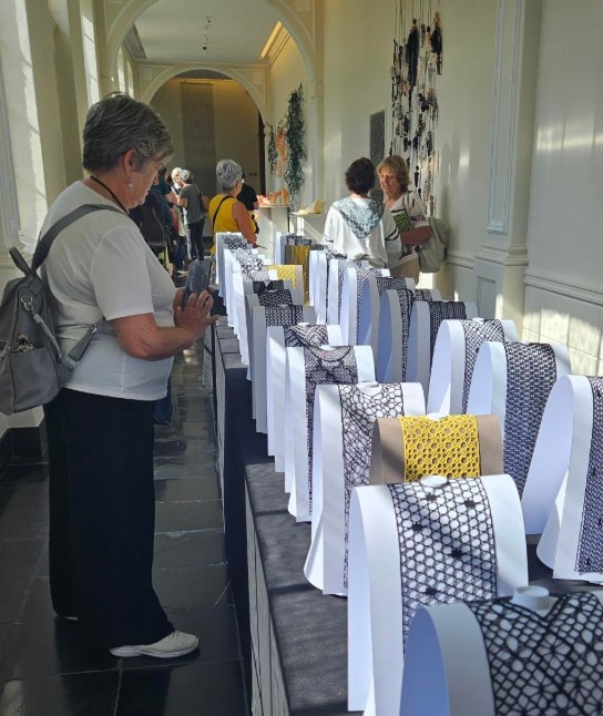 Bezoekers bekijken en fotograferen kunstwerken van textiel met patronen in de Abdij. (vergroot foto)