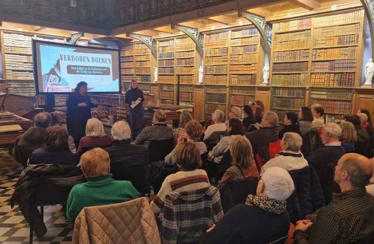 Publiek luistert naar presentatie over verboden boeken in de bibliotheek van de abdij van Bornem. (vergroot foto)