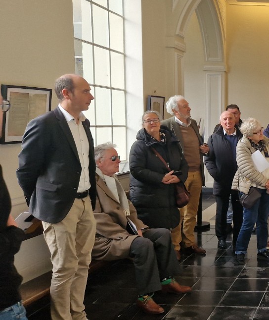 Groep mensen bekijkt zwart-wit foto’s in gang van de Abdij van Bornem (vergroot foto)