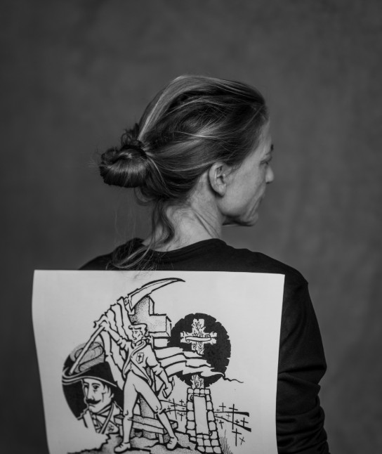 Zwart-wit foto van een vrouw met een tekening van een soldaat en een kruis op haar rug. (vergroot foto)