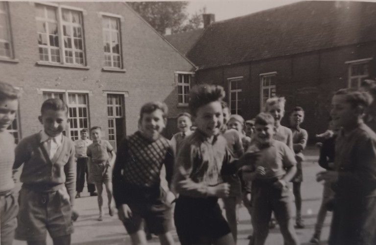 Zwart-wit foto van een groep jongens die speelt op een schoolplein. (vergroot foto)